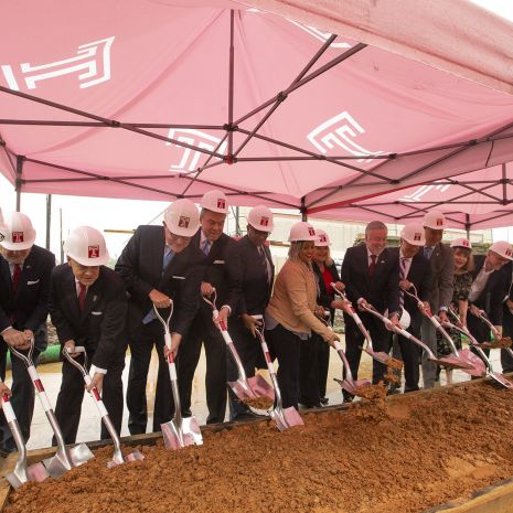 Temple University leaders in suits and hardhats pose with ceremonial shovels.