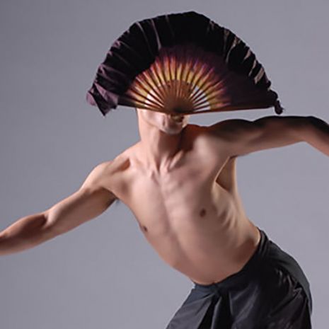 Male dancer with fan on gray background