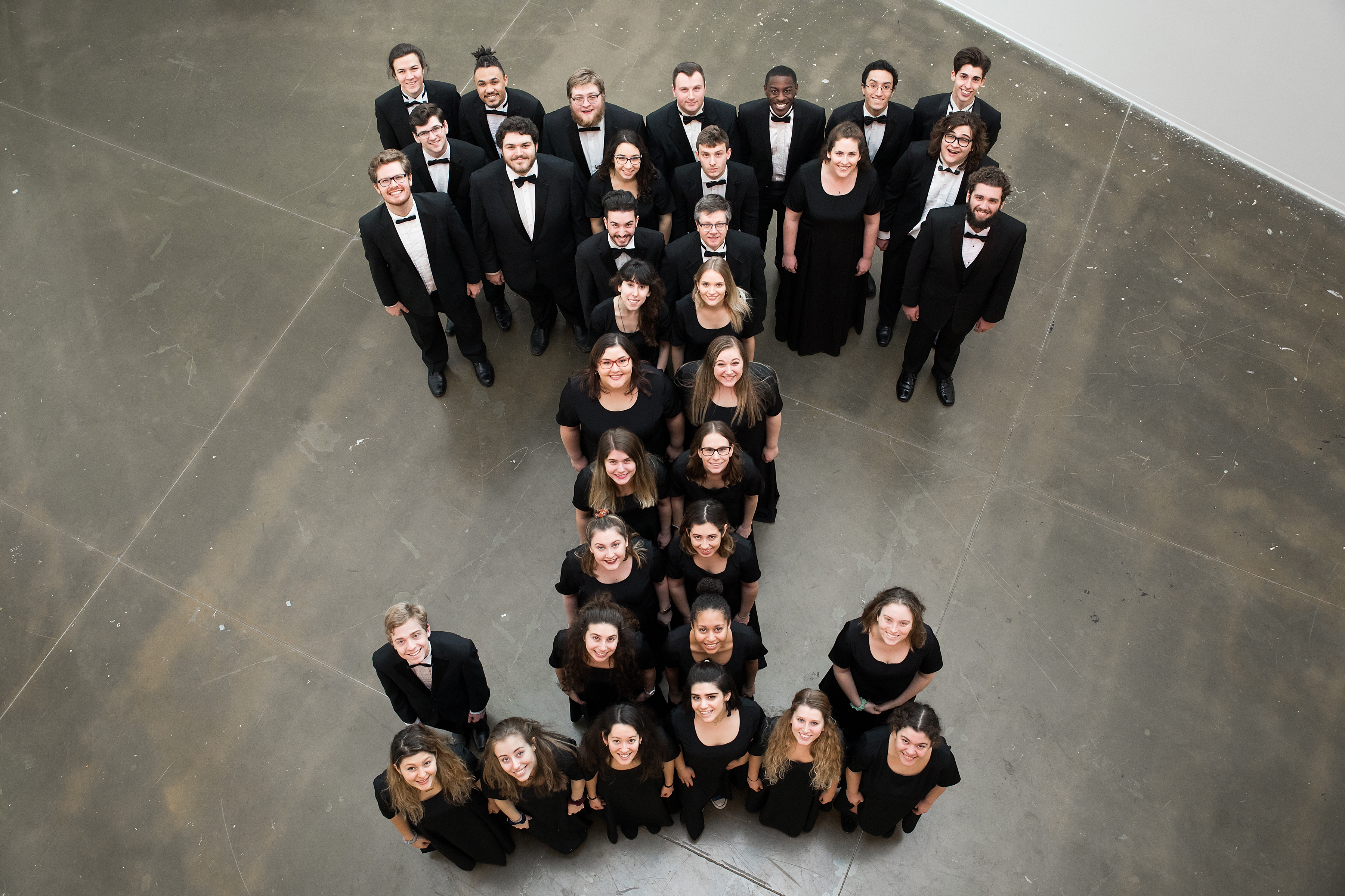 Image of students in concert dress looking up and standing in a "T" formation