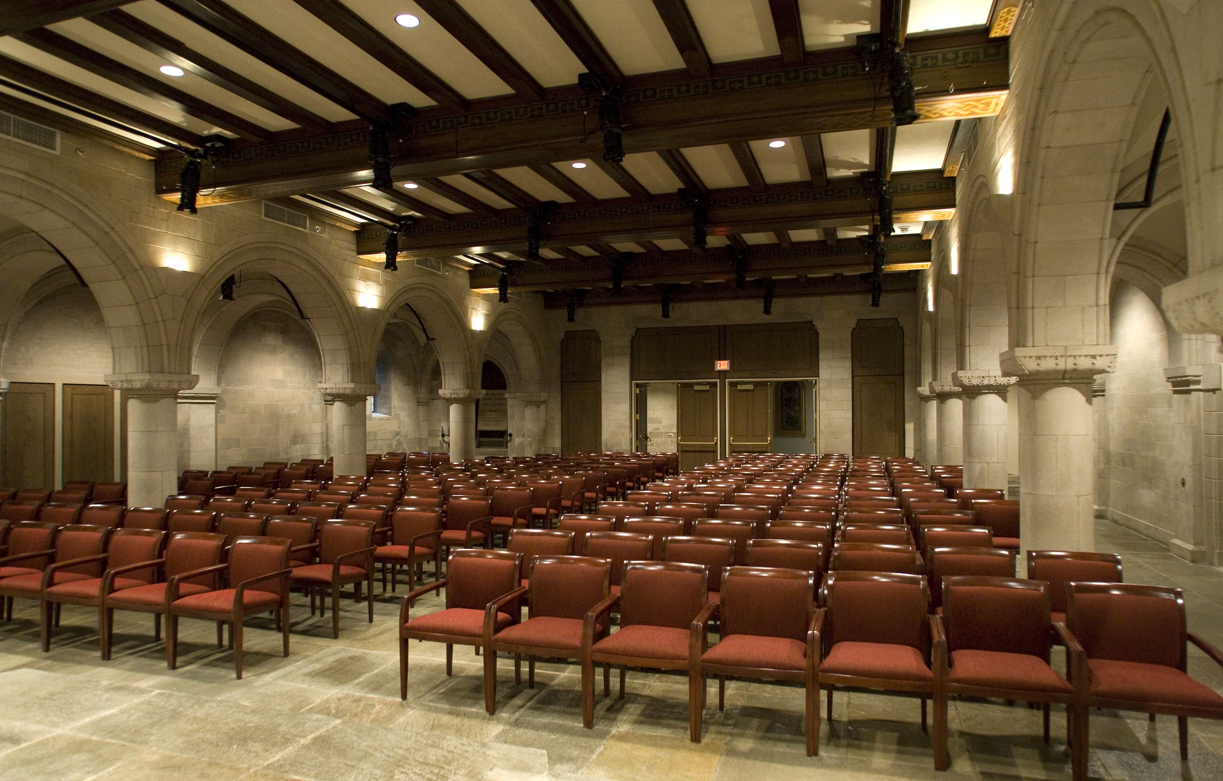 Rows of red upholstered armchairs for audience