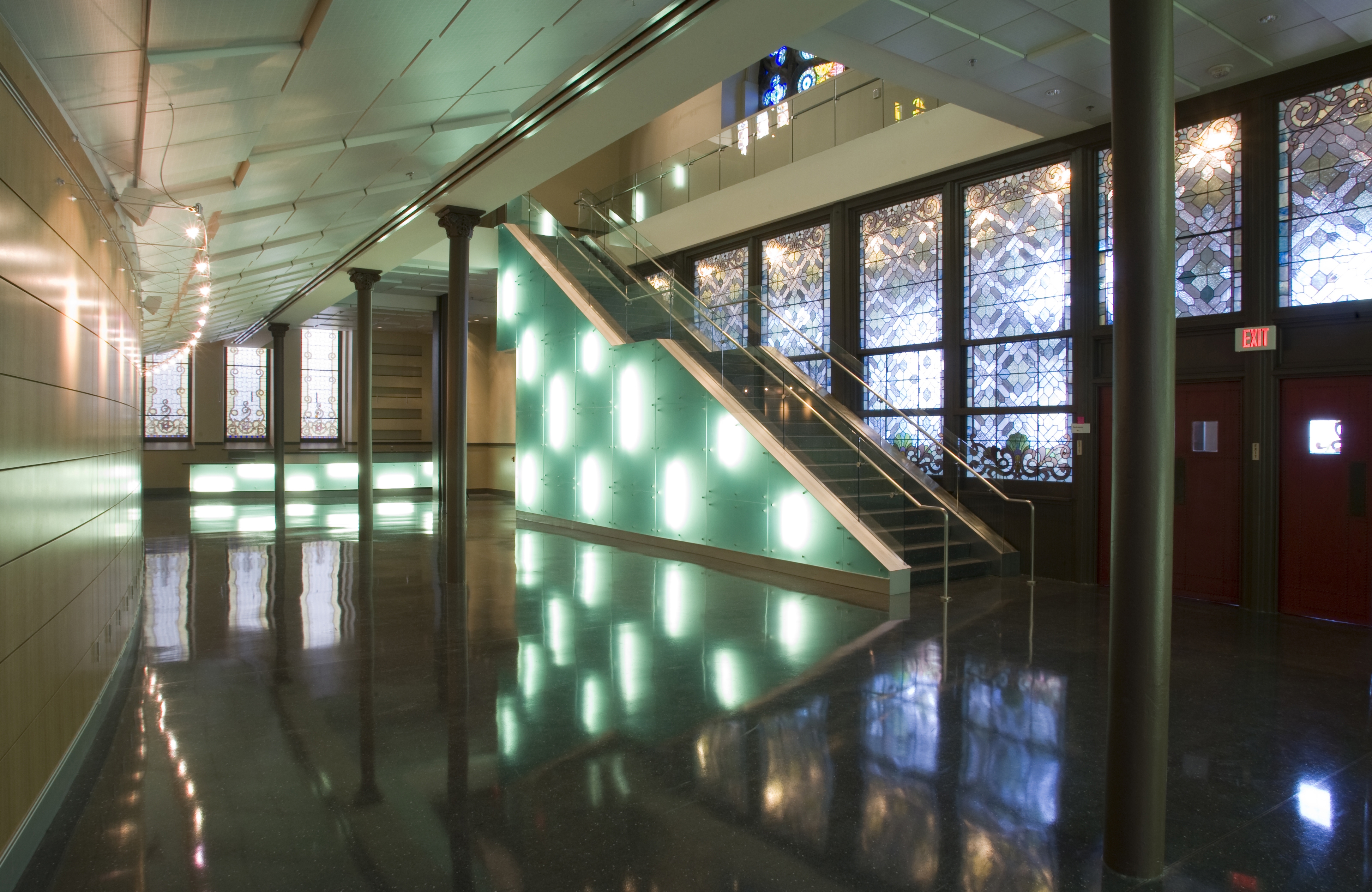 Performance hall lobby with illuminated staircase and stained glass windows