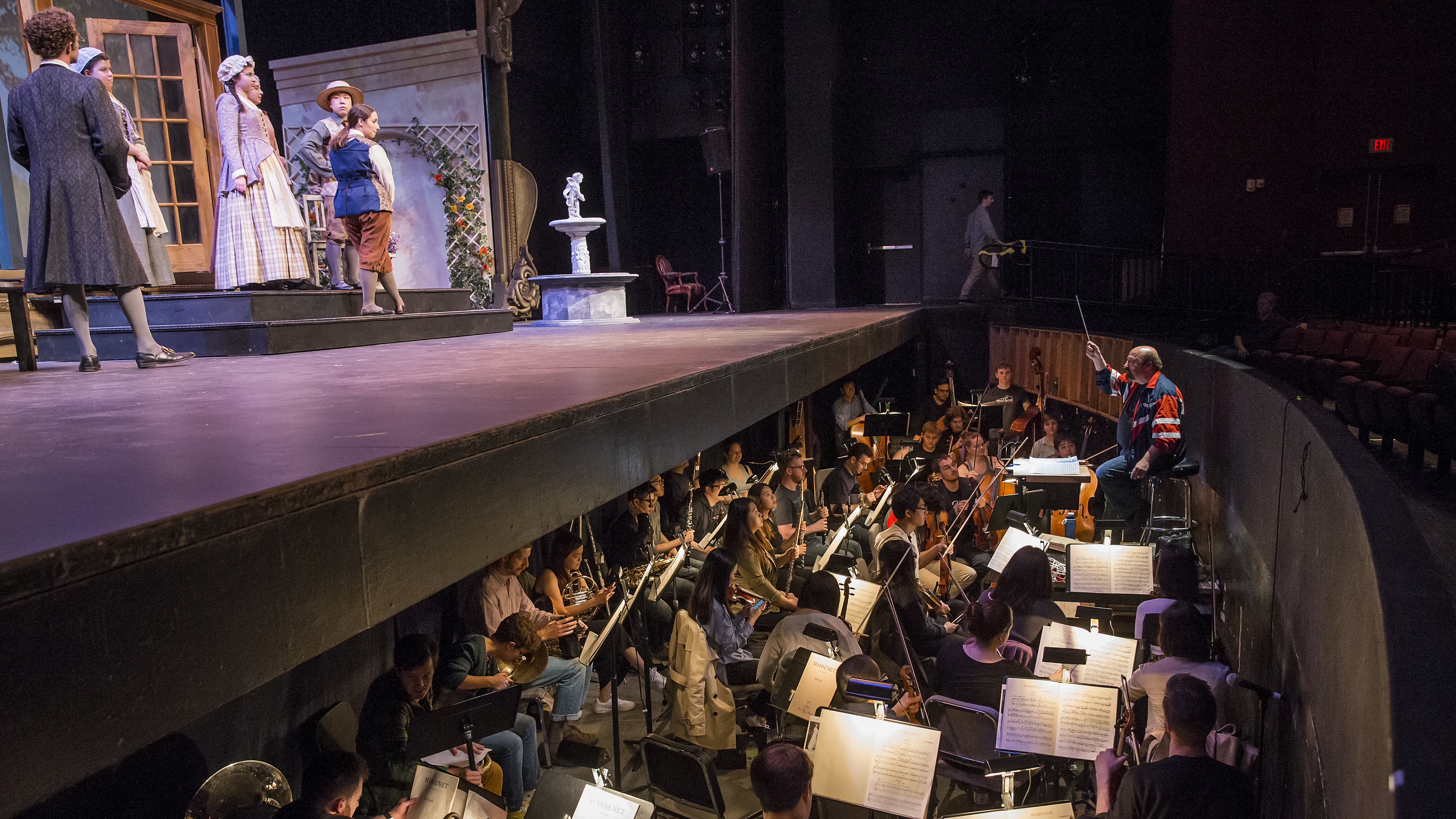 Opera rehearsal with pit orchestra and vocalists standing on stage above