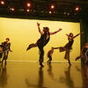 Dancers in Conwell Dance Theater performing against a yellow background