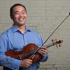 Man in blue shirt smiles while holding a viola