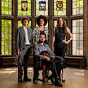 Three students stand behind a student seated in a chair holding a mandolin