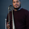 Jasyn Brazoban, wearing a dark sweater and holding a trombone