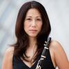 Woman with dark hair in black top holding a clarinet