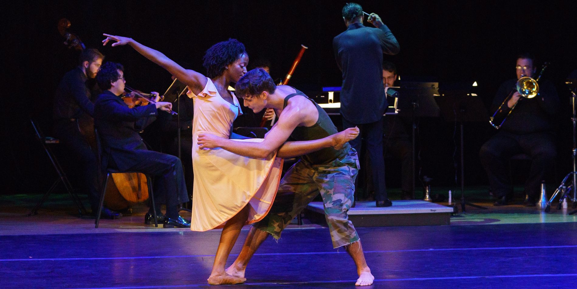 Two dancers in front of a chamber ensemble of musicians