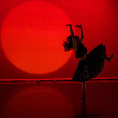 Shadow of a dancer in front of a red backdrop.