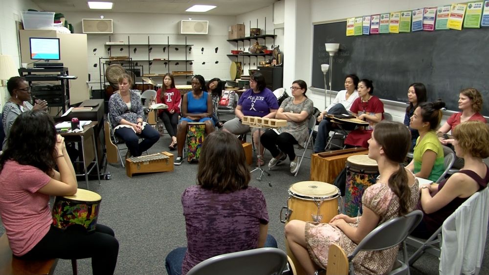 Photo of students in classroom sitting in a circle with percussion instruments in front of them