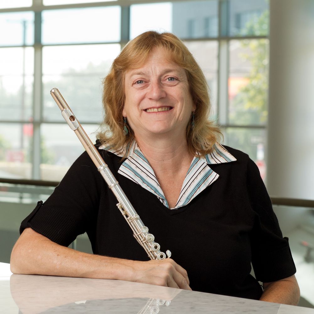 Headshot of blonde woman smiling and holding a flute