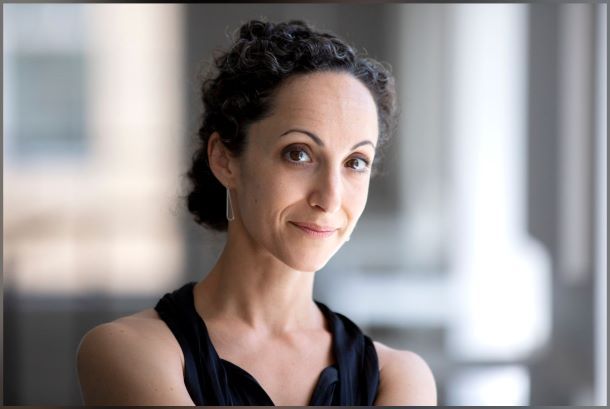 Headshot of woman with curly hair in a bun