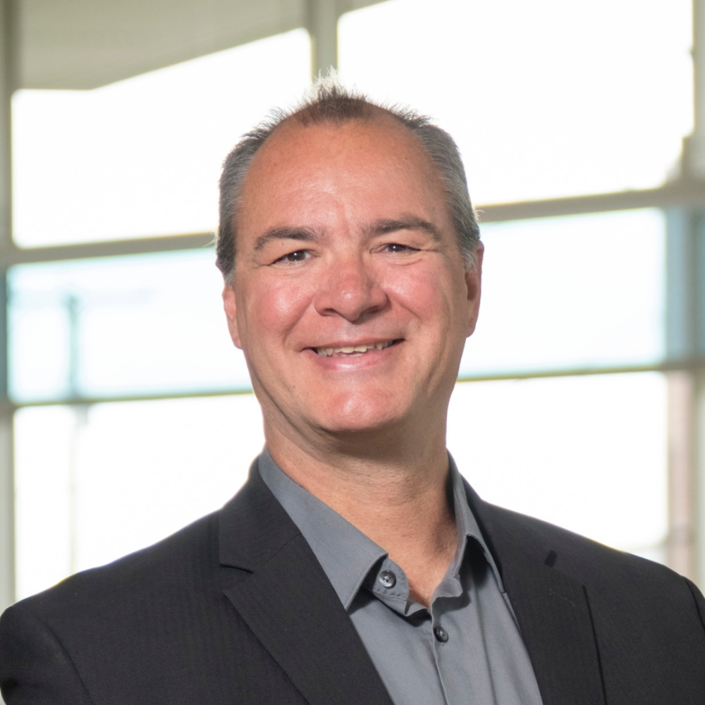 Photo of smiling man with colorful windows and bright sunlight in the background