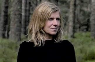 Headshot of a blonde woman in a forest, gazing sideways