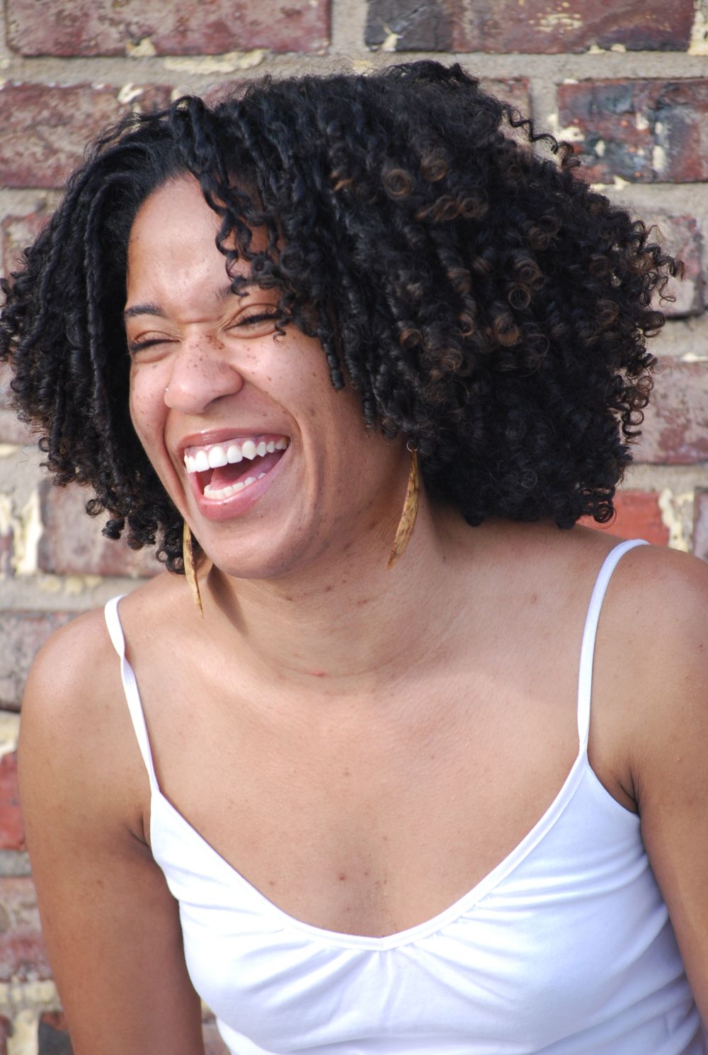 Photo of woman laughing against a brick wall background