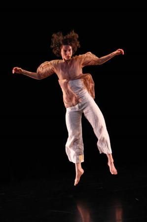 Woman jumping mid-air with arms extended, black background