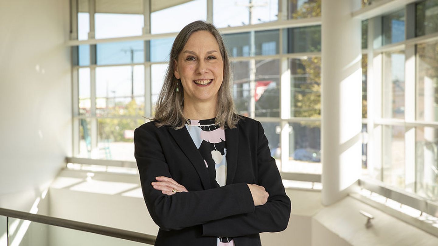 Portrait photo of Dr. Alison Reynolds in front of floor to ceiling windows