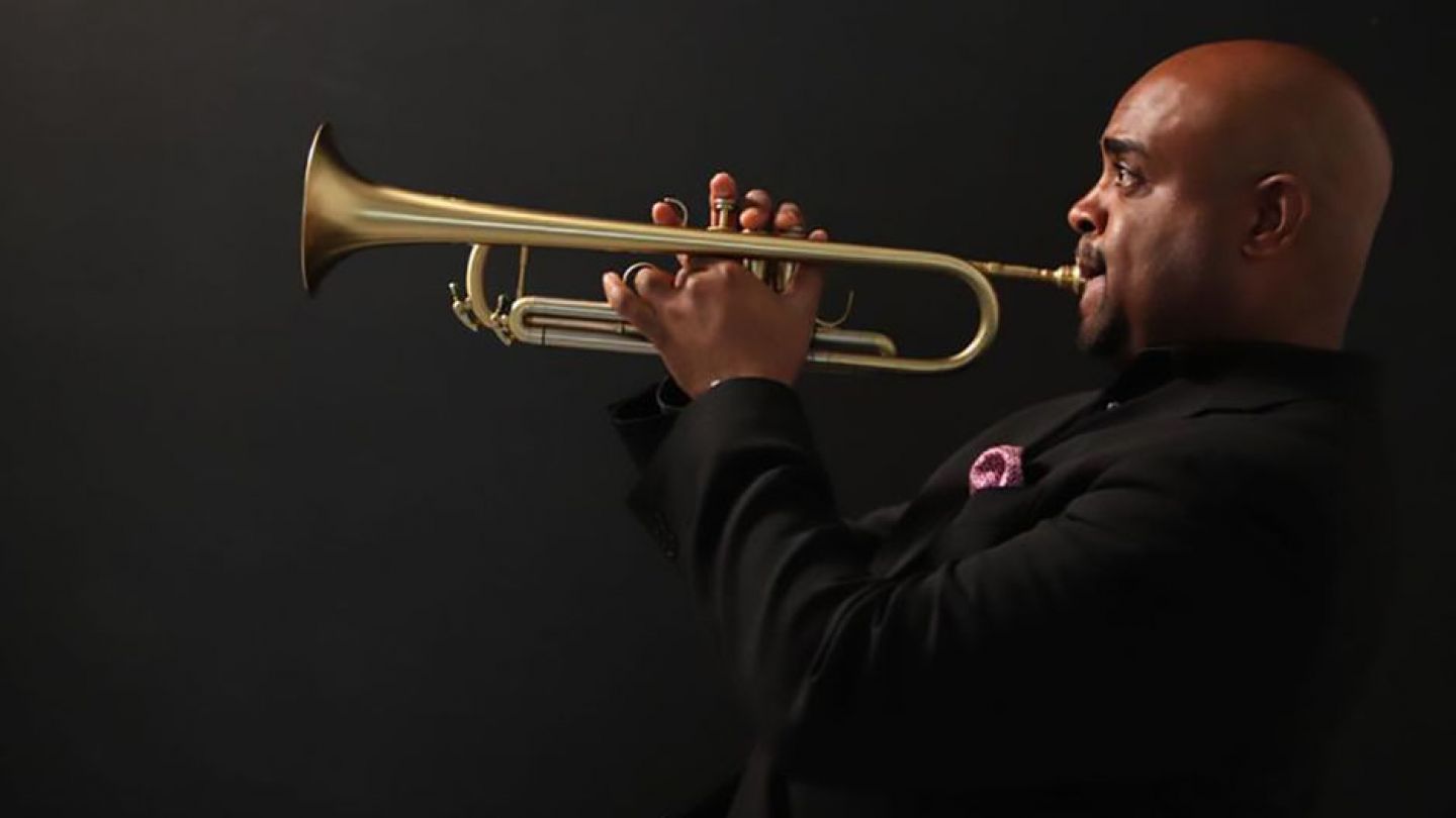 Terell Stafford playing the trumpet on a dark background