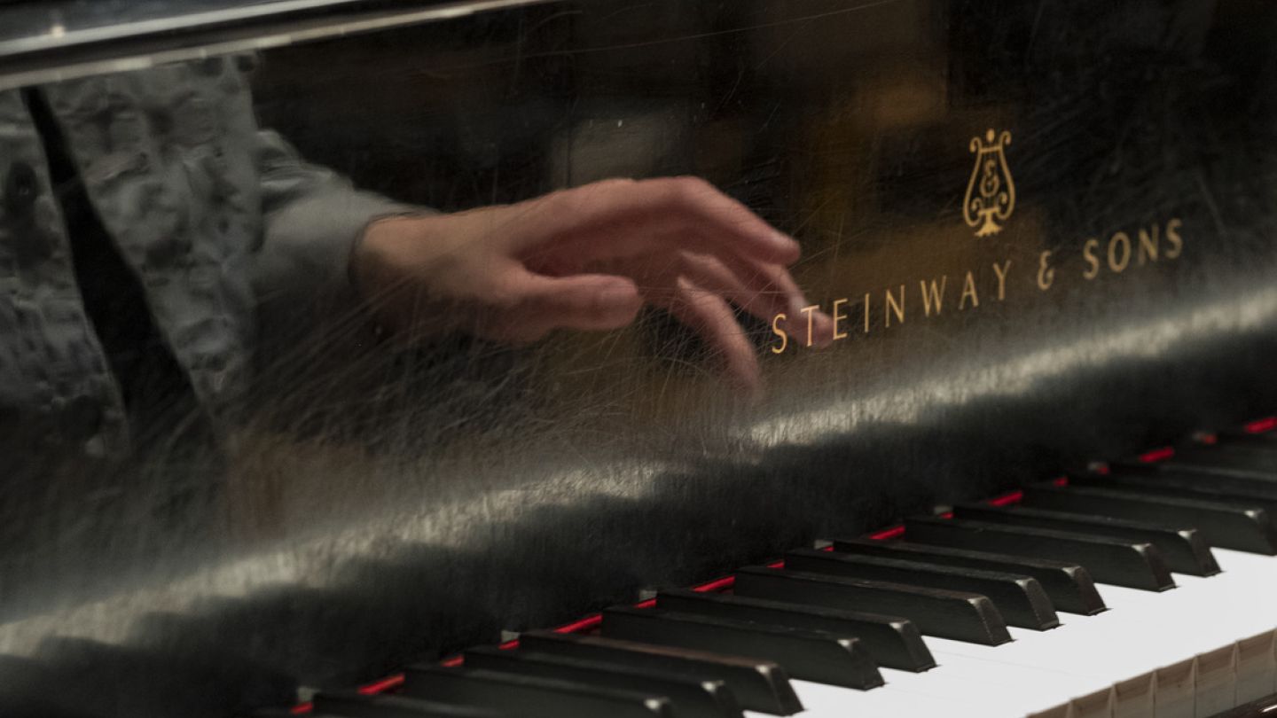 Hand playing a Steinway piano