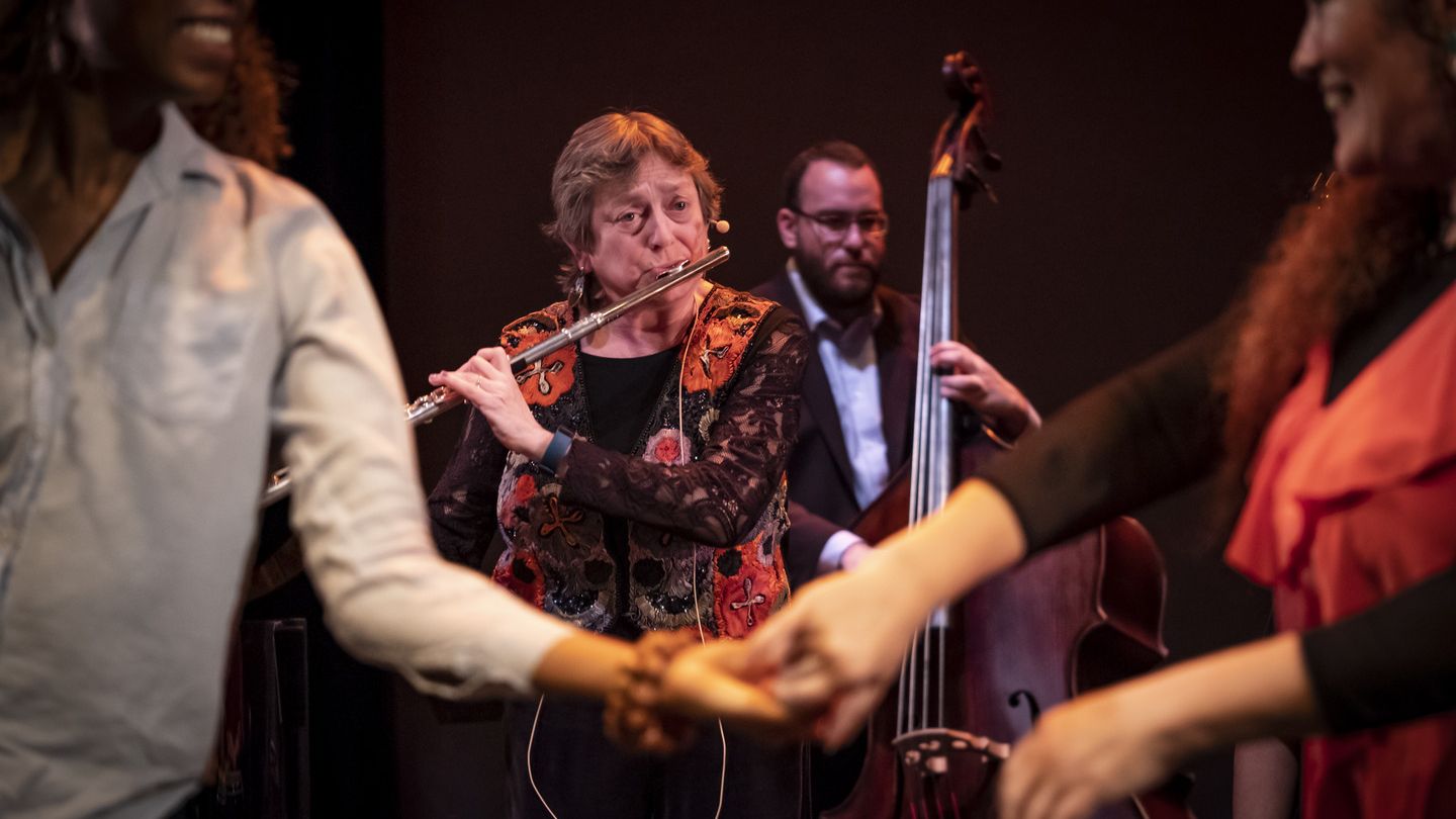 Image of Dr. Cynthia Folio playing the flute with dancers