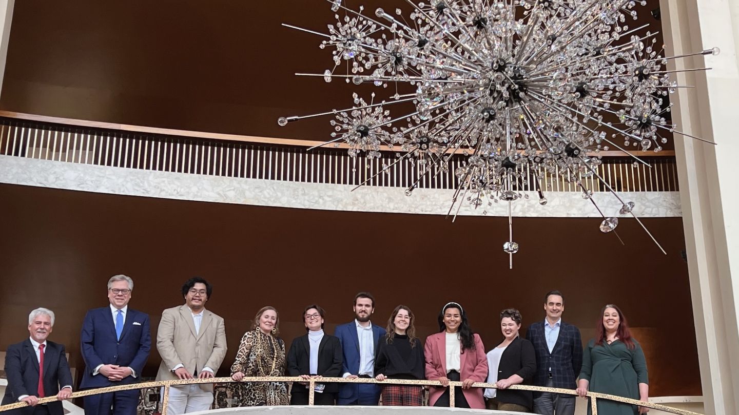 Photo of people posed with a chandelier fixture in the foreground