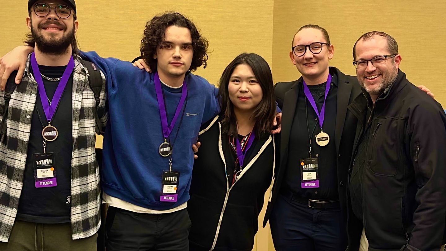 Photo of students with competition-winning medals, with professor