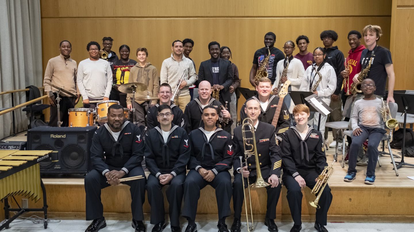Photo of students and Navy Band members on a stage together