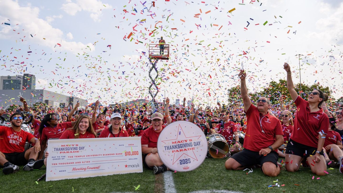 Photo of marching band members launching confetti in the air, smiling and celebrating