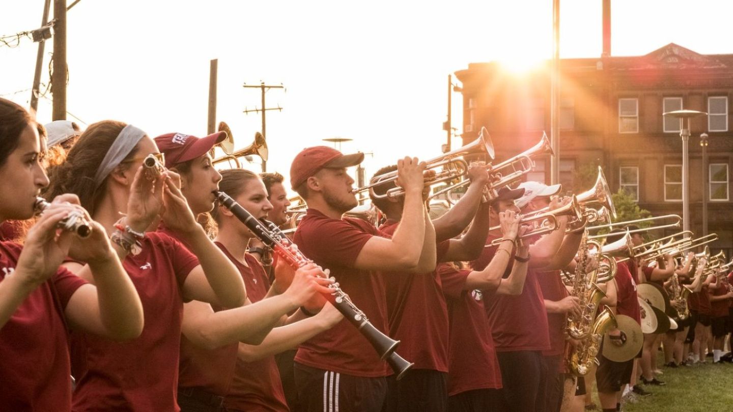 Photo of marching band members performing outside in the sunlight