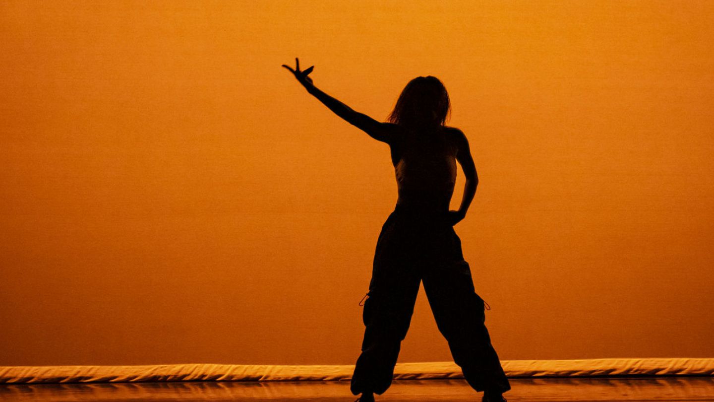 Photo of dancer silhouette against orange lighting/backdrop