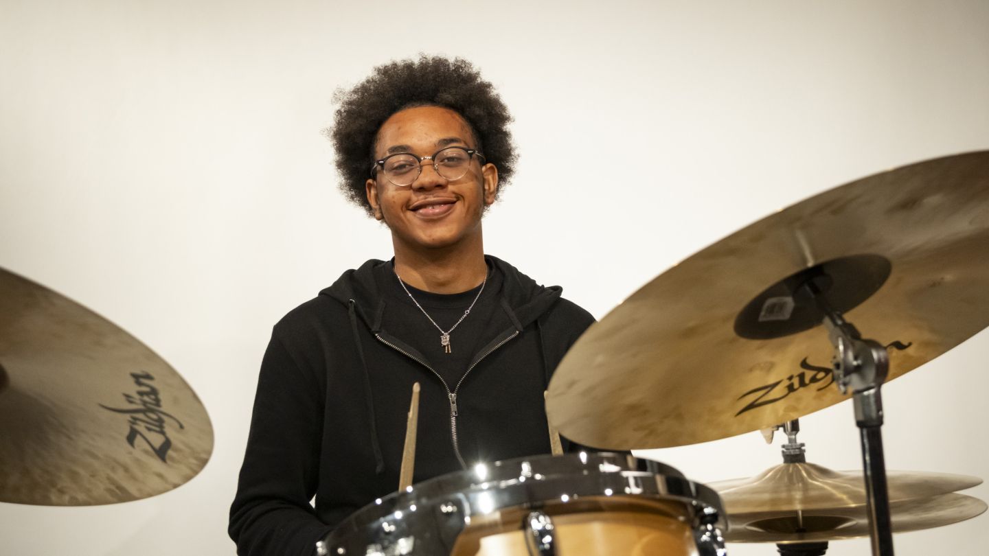 Photo of smiling jazz student sitting at the drums