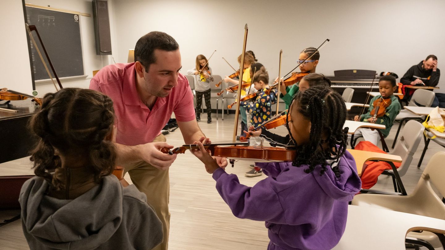 Teacher helping child with violin